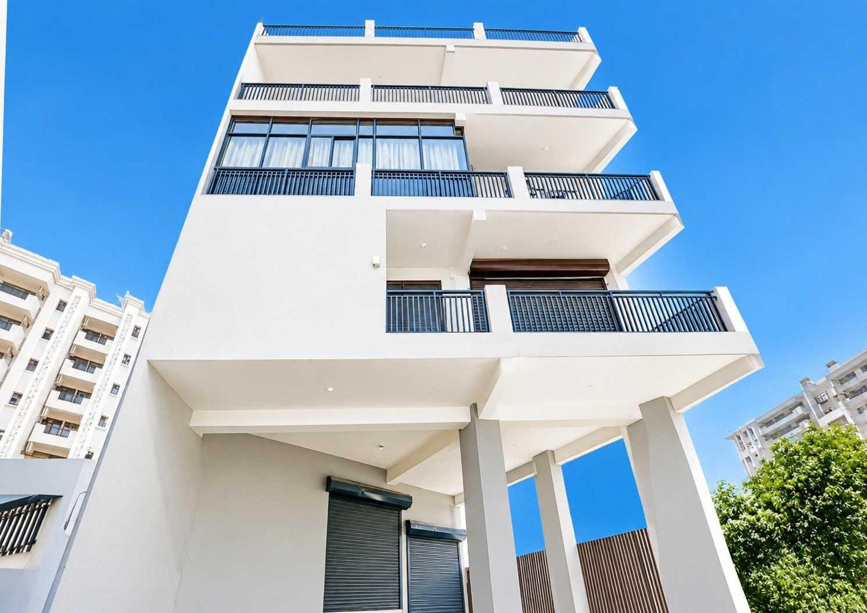 A multi-story building with balconies, large windows, and a clear sky.