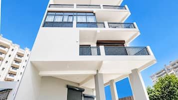 A multi-story building with balconies, large windows, and a clear sky.