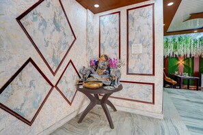 A room with a marble wall, a table with decorative items, and a green wall with hanging plants. - Classic Hotel Dream Palace (Danapur)