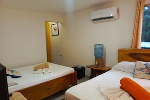 A room with two beds, a water dispenser, an air conditioner, and a framed picture on the wall. - Apartamentos y Villas D Angelo - Junior Suite 108 (Manzanillo)