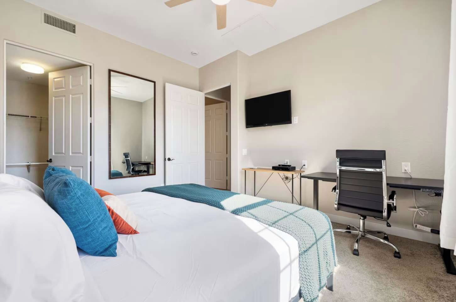 Een hotelkamer met twee bedden, een bureau, een stoel, een televisie en een deur naar een badkamer.