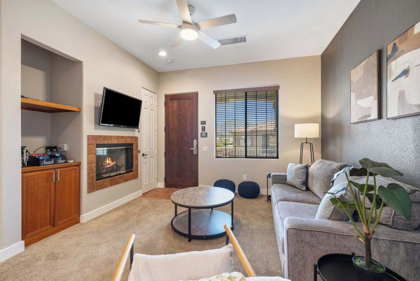 Una sala de estar con chimenea, televisor, sofá, mesa de centro y ventilador de techo.