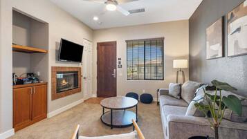 Una sala de estar con chimenea, televisor, sofá, mesa de centro y ventilador de techo.