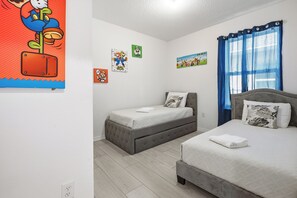 Ein Schlafzimmer mit zwei Betten, einem kleinen Tisch und Wandbildern.
