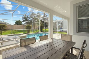 Uma varanda coberta com piscina, móveis de exterior e vista para o quintal.