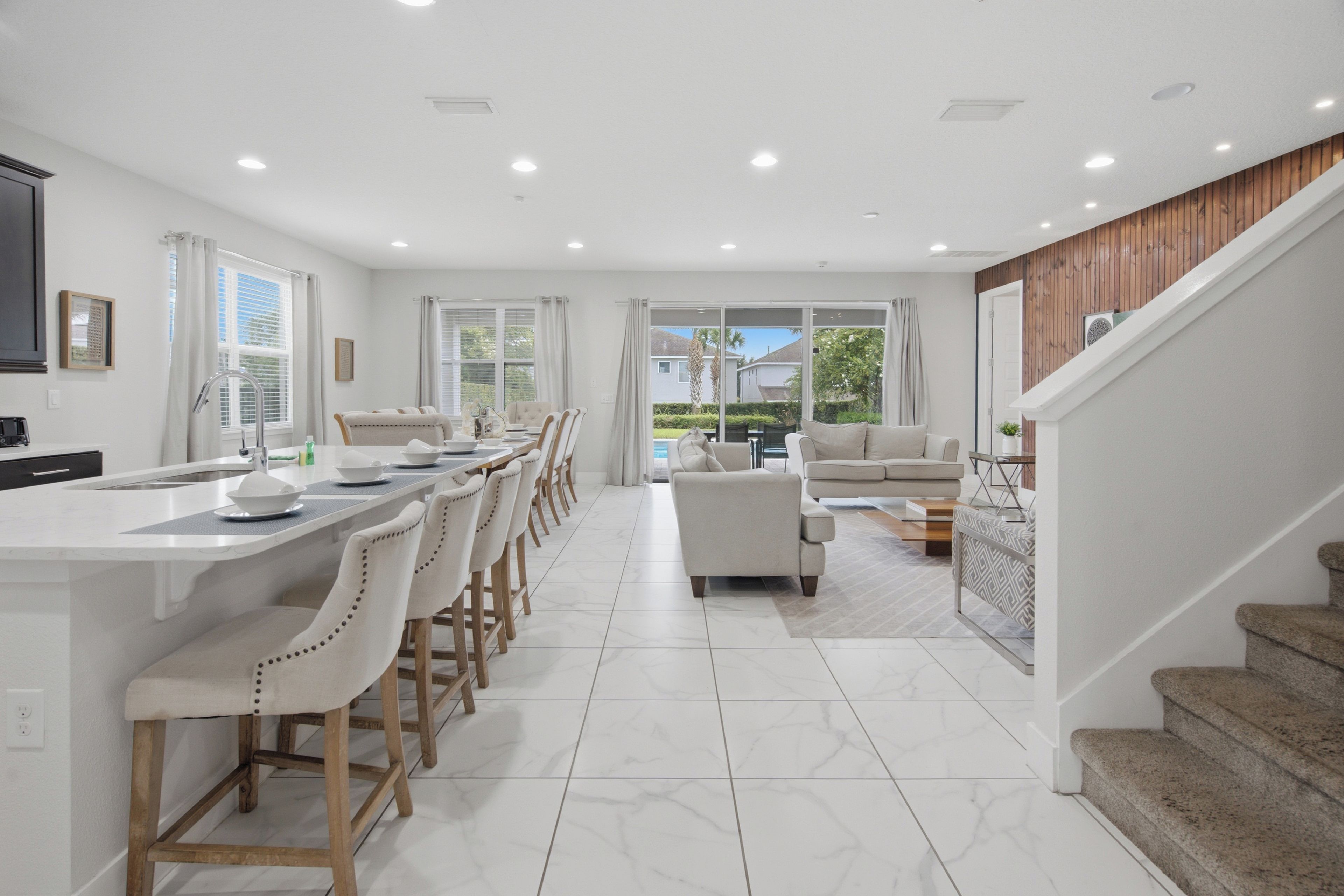 A modern kitchen with a dining area, a staircase, and a view of the outdoors.