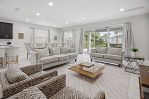 A modern living room with a sofa set, a coffee table, and a dining area with a table and chairs. - Prime Location Near Disney with Private Theater (Kissimmee)
