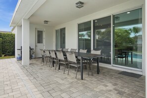Eine Terrasse mit Tisch, Stühlen, einem Gasflaschenlager und einer Tür.