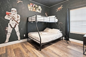 A bunk bed room with Star Wars-themed wall art, a window with blinds, and a wooden floor. - Star Wars & Mickey Kids Rooms | 18 Min to Disney (Kissimmee)
