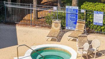 Un hidromasaje pequeño y redondo rodeado de sillones de descanso, con un cartel que indica las normas del spa y la prohibición de buceo.
