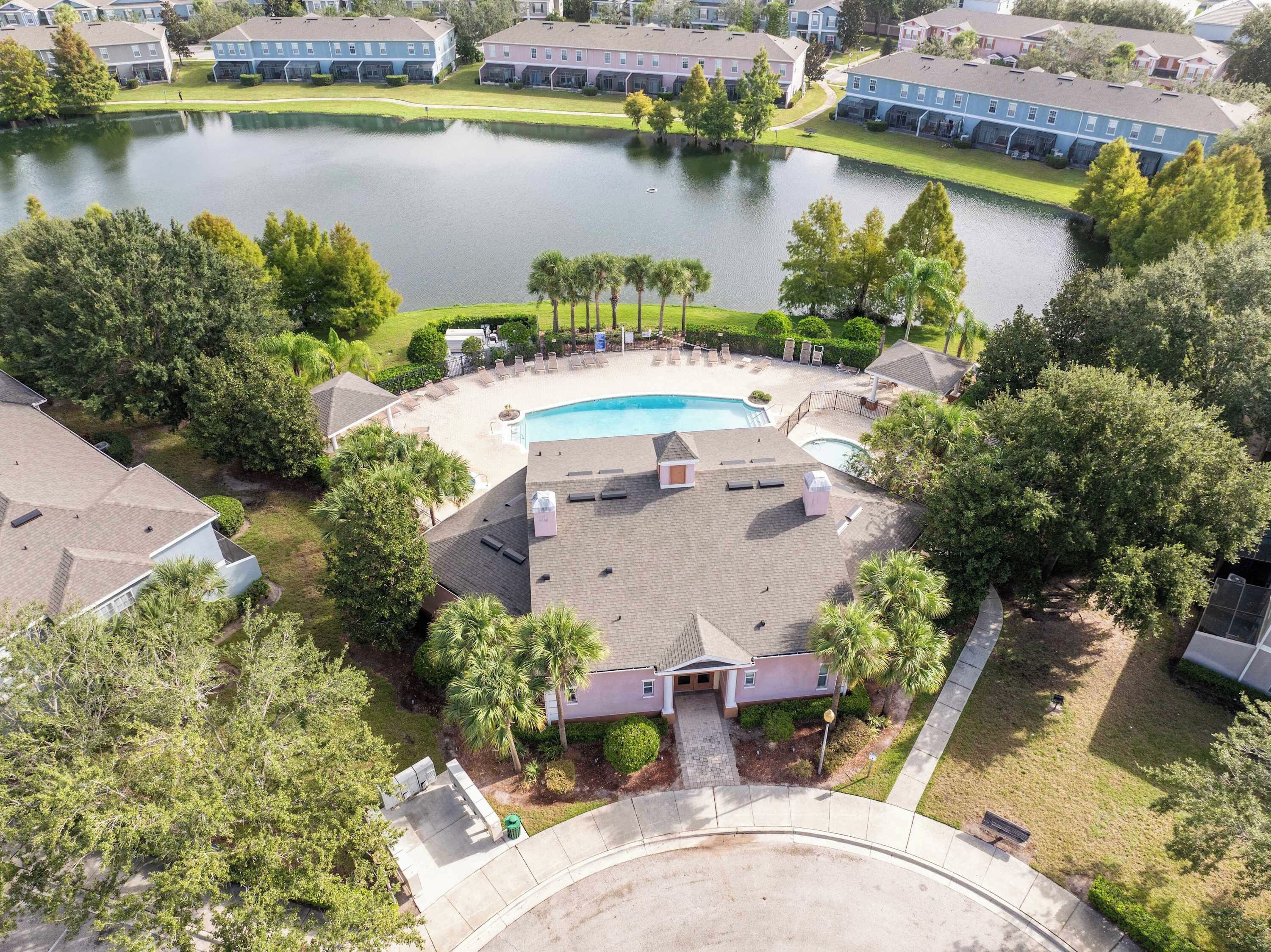 A residential area with a swimming pool surrounded by lounge chairs and palm trees.