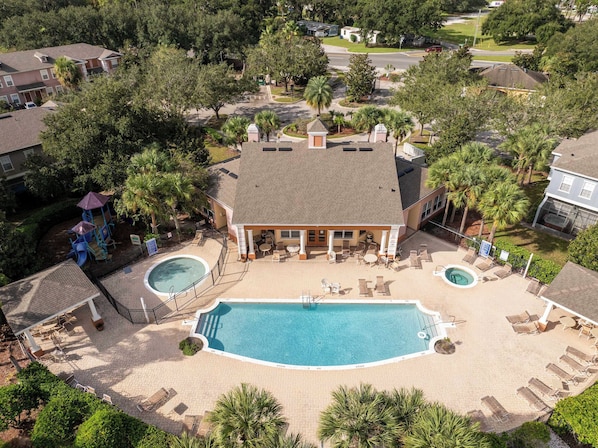 Un resort con una amplia piscina, tumbonas y una zona de juegos para niños.