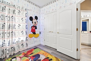 A room with a Mickey Mouse mural, white doors, and a colorful rug. - Star Wars & Mickey Kids Rooms | 18 Min to Disney (Kissimmee)