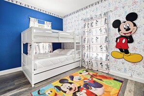 A child's room with a bunk bed, Mickey Mouse-themed wallpaper, and a colorful Mickey Mouse rug. - Star Wars & Mickey Kids Rooms | 18 Min to Disney (Kissimmee)
