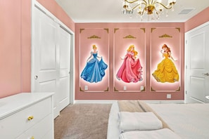 A bedroom with a bed, a dresser, and a wall with three princess-themed posters. - Kids Slide Room, Arcade & Game Room, Sleeps 24 (Clermont)
