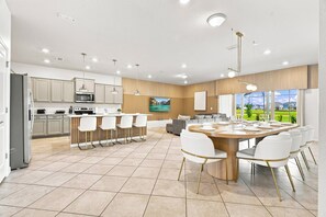 Une cuisine moderne dotée d’un îlot central, d’un coin bar et d’un espace repas avec une grande table et des chaises.