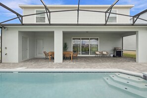 A modern house with a covered patio, a pool, and a barbecue area. - Kids Slide Room, Arcade & Game Room, Sleeps 24 (Clermont)