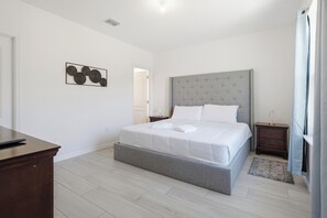 A bedroom with a bed, bedside tables, a nightstand, a desk, and a wall-mounted artwork. - Super Mario Room & Lake View Patio, Sleeps 8 (Kissimmee)