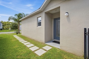 A modern house with a well-maintained lawn and a pathway leading to the entrance. - Super Mario Room & Lake View Patio, Sleeps 8 (Kissimmee)