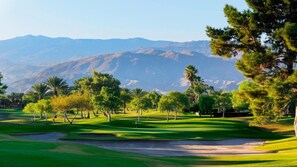Ein Golfplatz mit freiem Blick auf die Berge im Hintergrund.