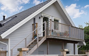 A house with a steeply pitched roof, a wooden staircase leading to a balcony, and a visible window. - Cozy home in ängelholm with private swimming pool, can be inside or outside (Ängelholm)
