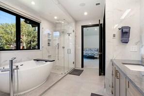 Ein modernes Badezimmer mit freistehender Badewanne, einer Duschkabine und einem Waschtisch.