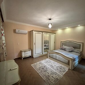 Ein Schlafzimmer mit Bett, Kleiderschrank, Nachttisch und Klimaanlage.