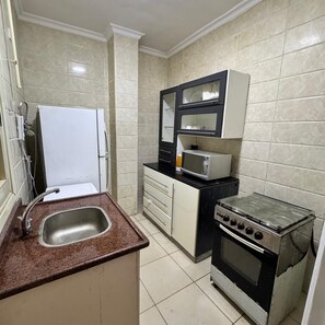 A compact kitchen with a sink, a white refrigerator, a microwave, and a small stove. - 2-bedroom apartment in marvelous Giza with AC for relaxing stays (Giza)