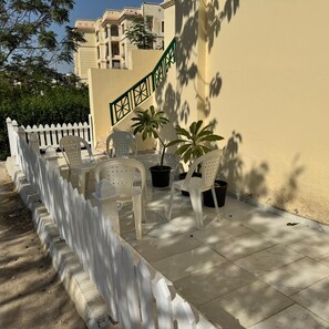 Eine Terrasse mit Sitzgelegenheiten im Freien, Blumentöpfen und einem weißen Zaun.