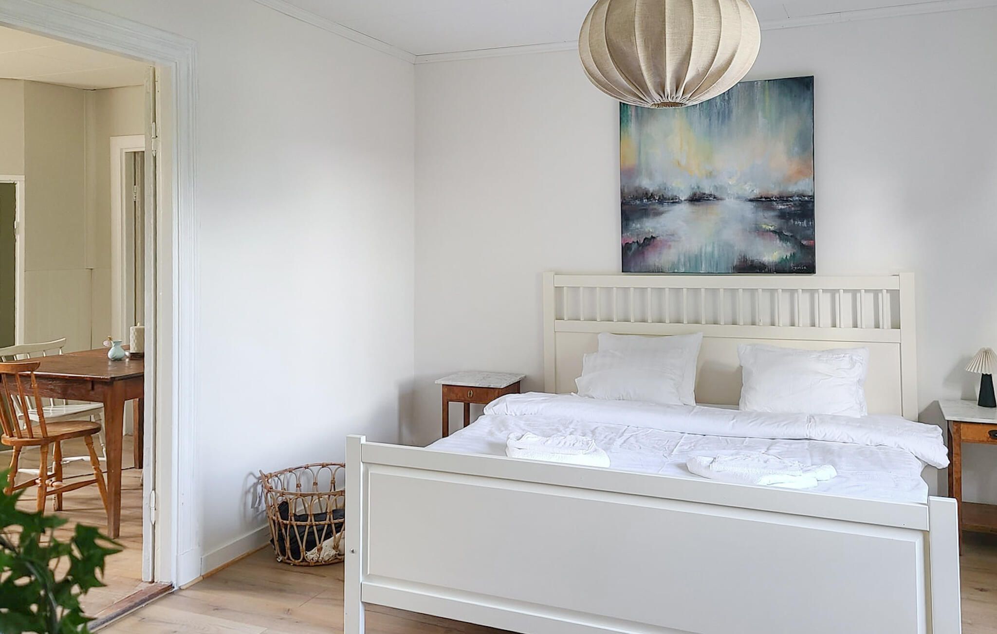 Ein Schlafzimmer mit einem Bett, einem Nachttisch, einer Lampe und einem Bild an der Wand.