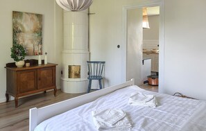 A bedroom with a bed, a wooden dresser, a chair, a painting, and a kitchen visible through an open door. - 4 bedroom gorgeous home in Visselfjärda (Visselfjärda)