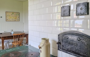 A room with a tiled wall, a wooden table with chairs, a metal container, and a door with decorative elements. - 4 bedroom gorgeous home in Visselfjärda (Visselfjärda)