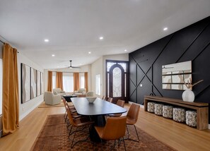 A modern dining area with a long table, multiple chairs, and a decorative wall. - Sundance - Private Pool - Mins to Kierland Commons (Scottsdale)
