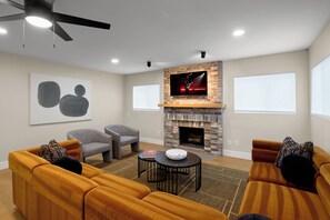 A living room with a fireplace, two sofas, a TV, and a ceiling fan. - Sundance - Private Pool - Mins to Kierland Commons (Scottsdale)