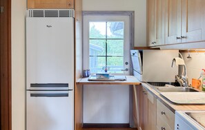 A compact kitchen with a built-in refrigerator, a window with a view of trees, and a sink with a faucet. - 4 bedroom nice home in Kyrkesund (Kyrkesund)