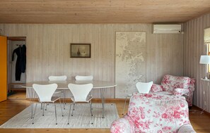 Ein Zimmer mit einem runden Tisch, weißen Stühlen, einem blumengemusterten Sofa, einer Karte an der Wand und einer Klimaanlage.