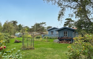Ein Haus mit gepflegtem Garten, einer Holzkonstruktion und einem Holzstapel.