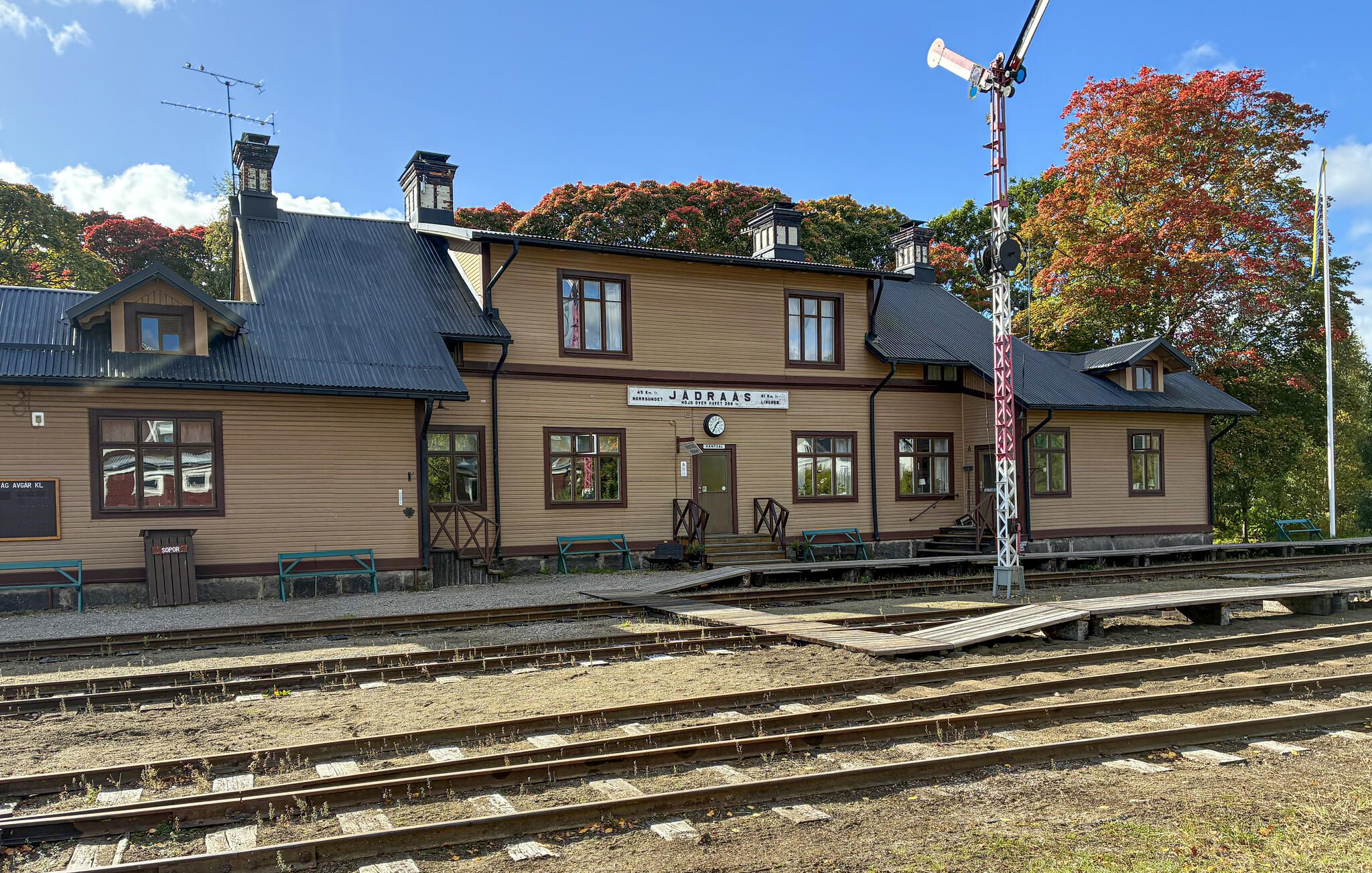 Un bâtiment de gare avec plusieurs voies, des bancs et une horloge.