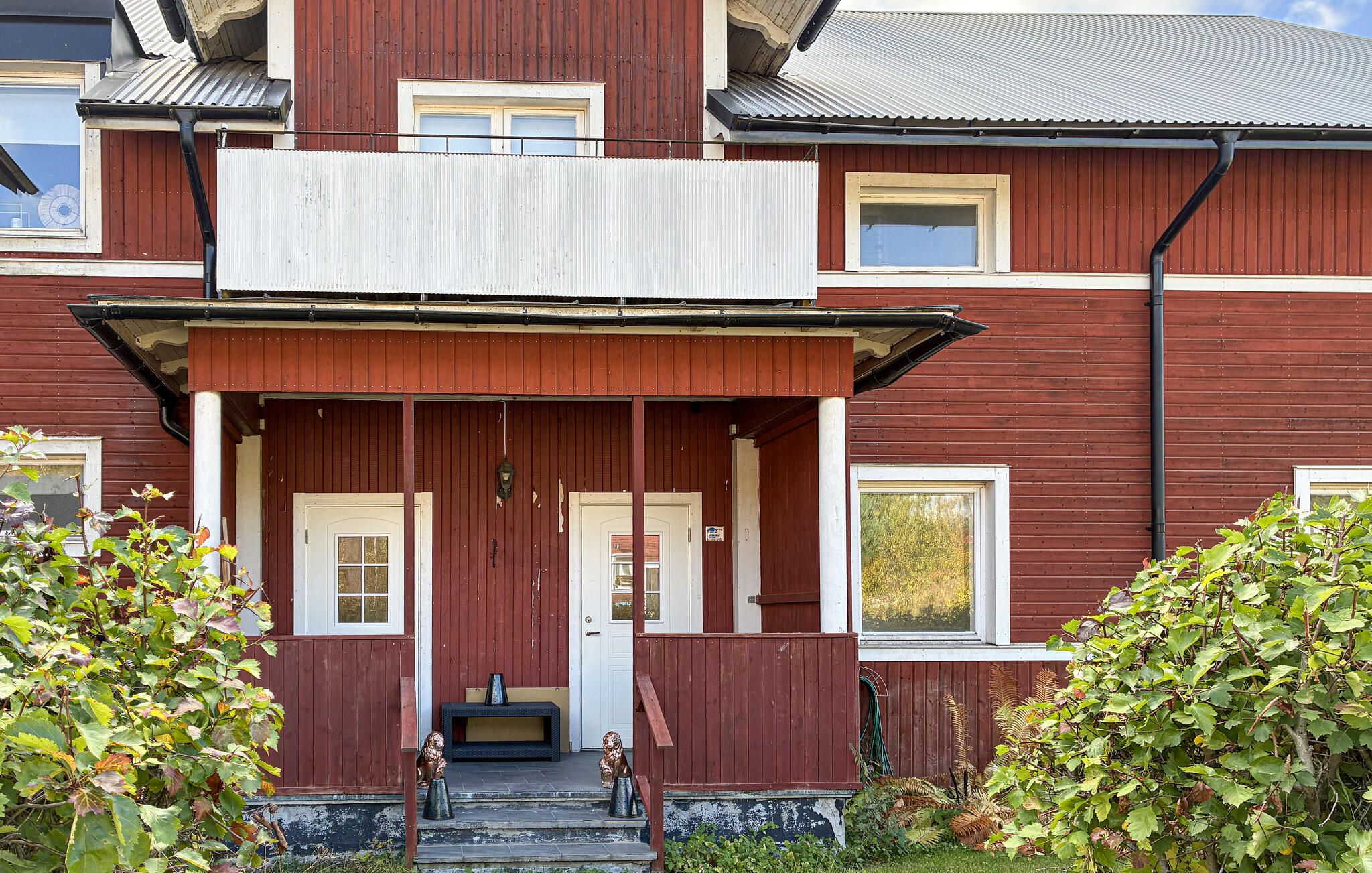 A two-story building with a porch, a front door, and a small bench.