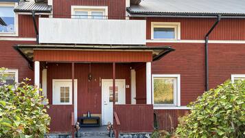 A two-story building with a porch, a front door, and a small bench.