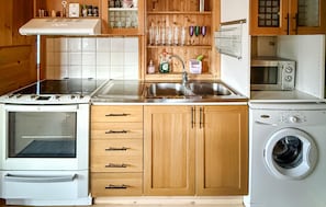 A compact kitchen with a stove, sink, and washing machine.