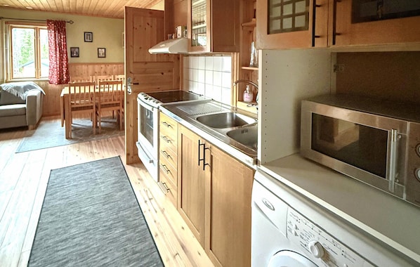 A compact kitchen with wooden cabinets, a built-in oven, a microwave, and a sink.