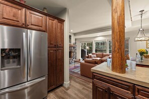 Eine Küche mit Holzschränken, einem Edelstahlkühlschrank und einer großen Holzsäule.