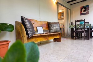 A wooden bench with a certificate, a dining area with chairs, and a potted plant. - Apartamentos y Villas D Angelo - Superior Apartment with Terrace 103 (Manzanillo)