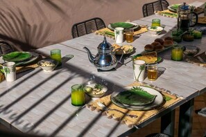A dining table set with various dishes, drinks, and a teapot, suggesting a meal setting. - Riad – Heated Pool & Rooftop in the Heart of the Medina (Marrakech)