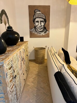 A living room with a patterned cabinet, a woven basket, and a sofa with pillows. - Riad – Heated Pool & Rooftop in the Heart of the Medina (Marrakech)