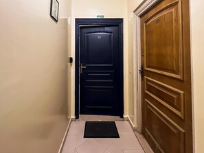 Ein Korridor mit einer dunkelblauen Tür, die mit der Nummer 19 gekennzeichnet ist, einer Holztür mit der Nummer 20 und einem gefliesten Boden.