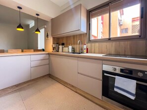 Une cuisine moderne dotée d’un four encastré, d’un évier et de luminaires suspendus.