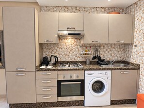 A compact kitchen with a built-in oven, a microwave, a coffee maker, and a washing machine. - Guéliz - Stylish Apartment with Balcony (Marrakesh)