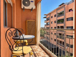 Uma varanda com mesa, cadeiras, um ventilador e uma janela.